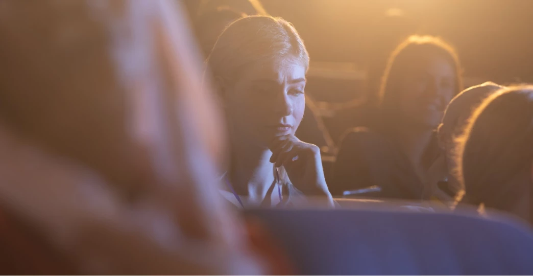 young businesswoman thinking and looking down while sitting in the auditorium