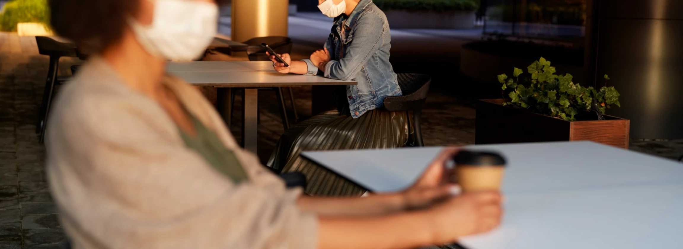 People in face mask sitting alone in a cafe outdoors