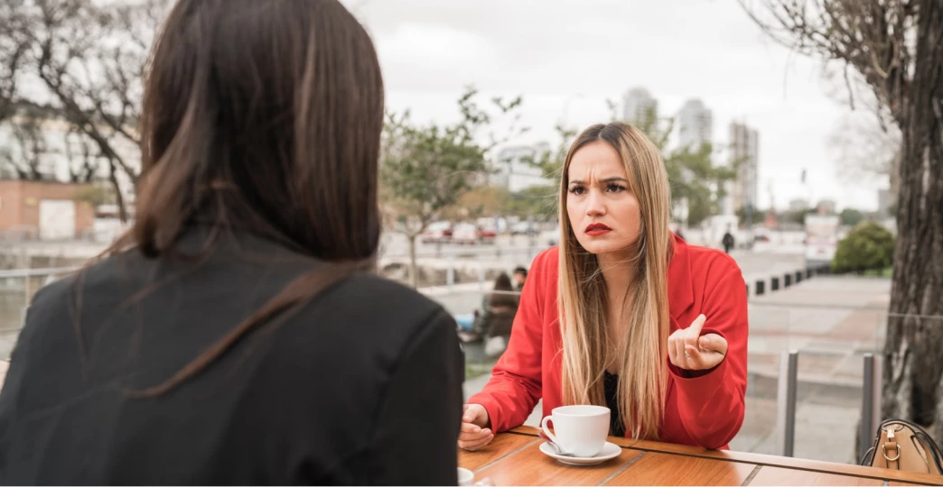 Two angry friends discussing while sitting at coffee shop