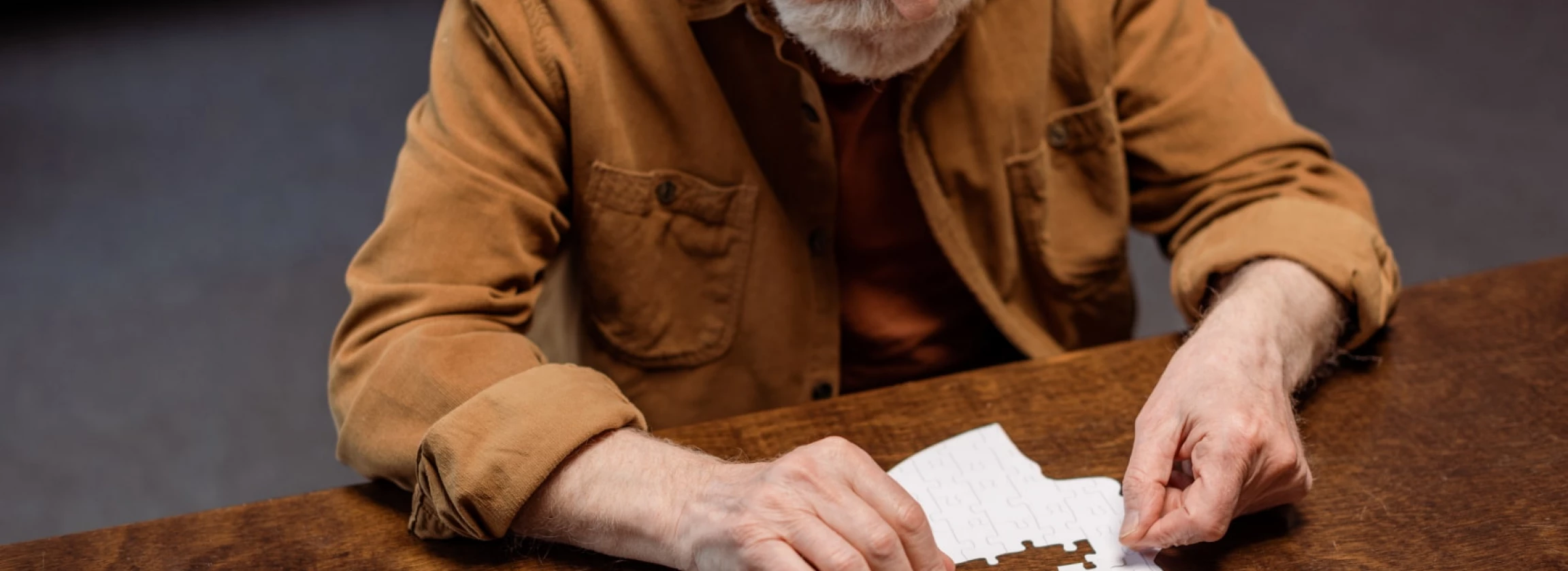 high angle view of senior man playing jigsaw puzzle as dementia therapy