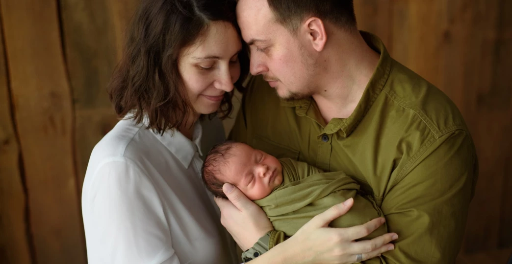 parents hold their newborn son in their arms