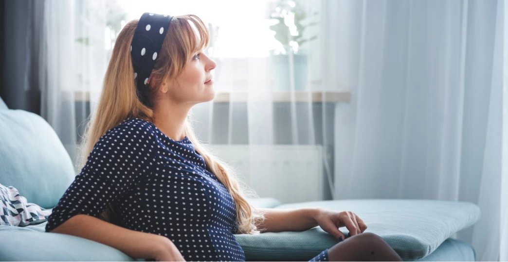 smiling woman sitting on floor at home dreaming and thinking about something