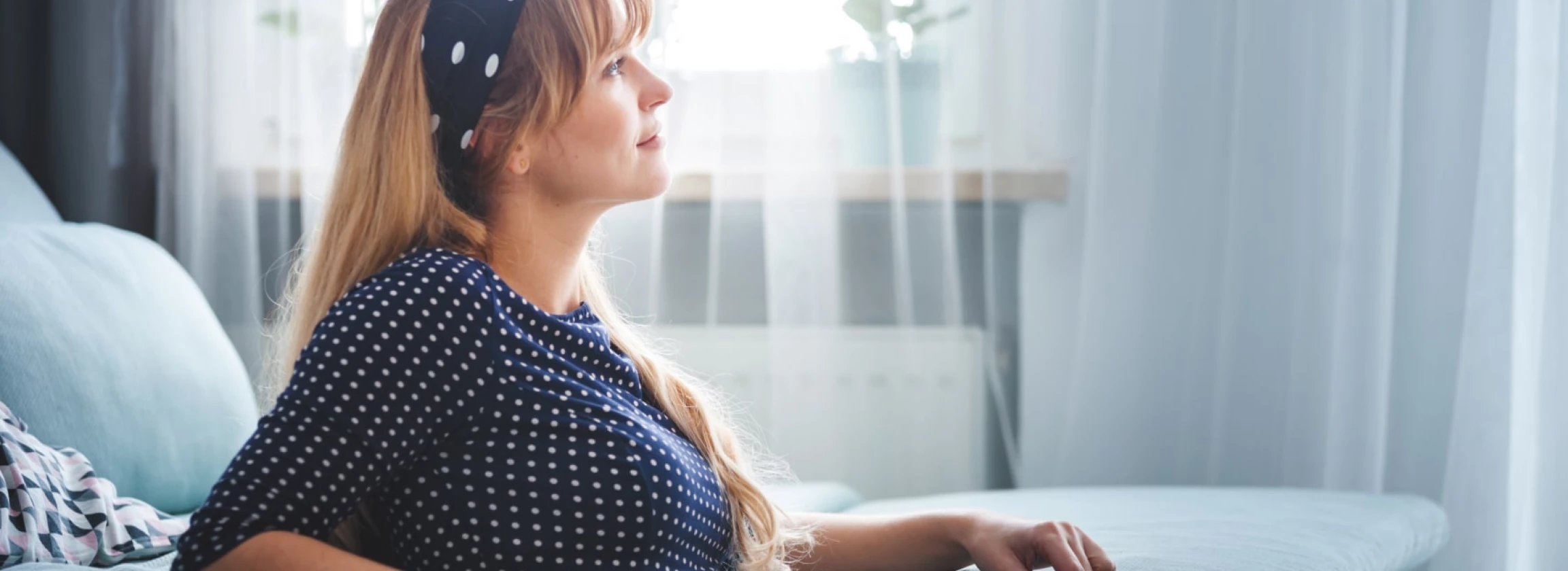 smiling woman sitting on floor at home dreaming and thinking about something