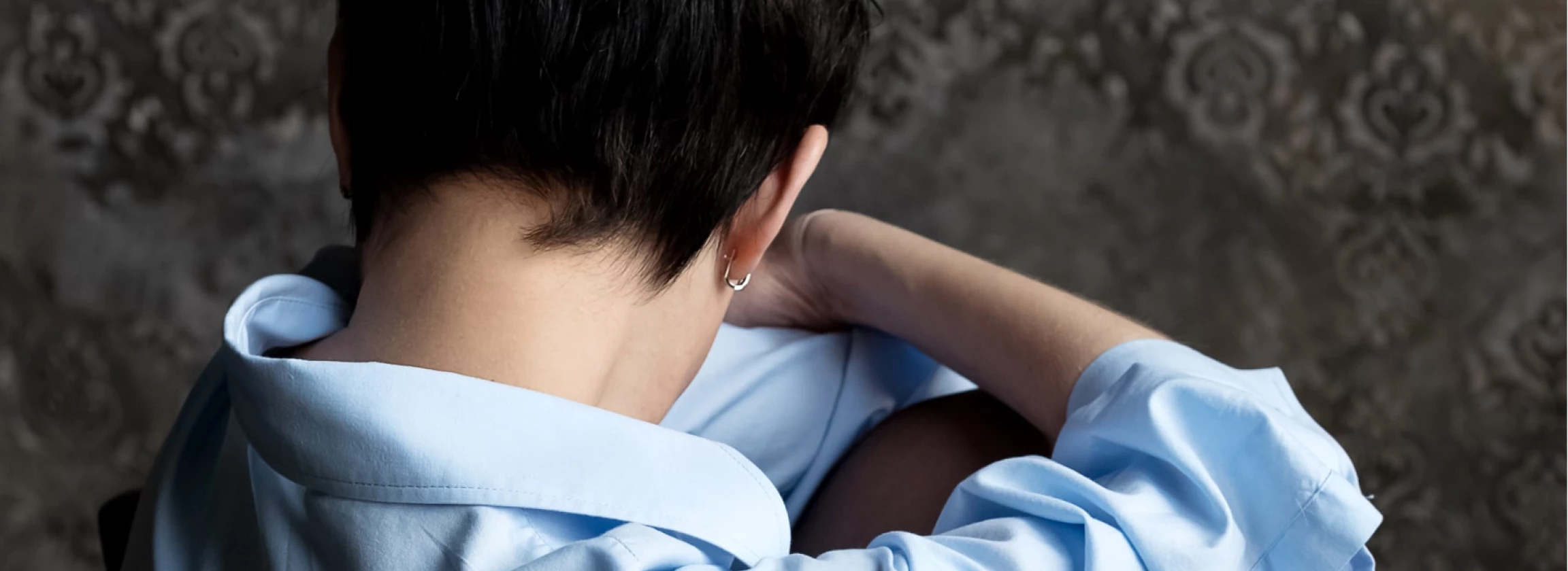 sad woman sits with her head bowed to her knees