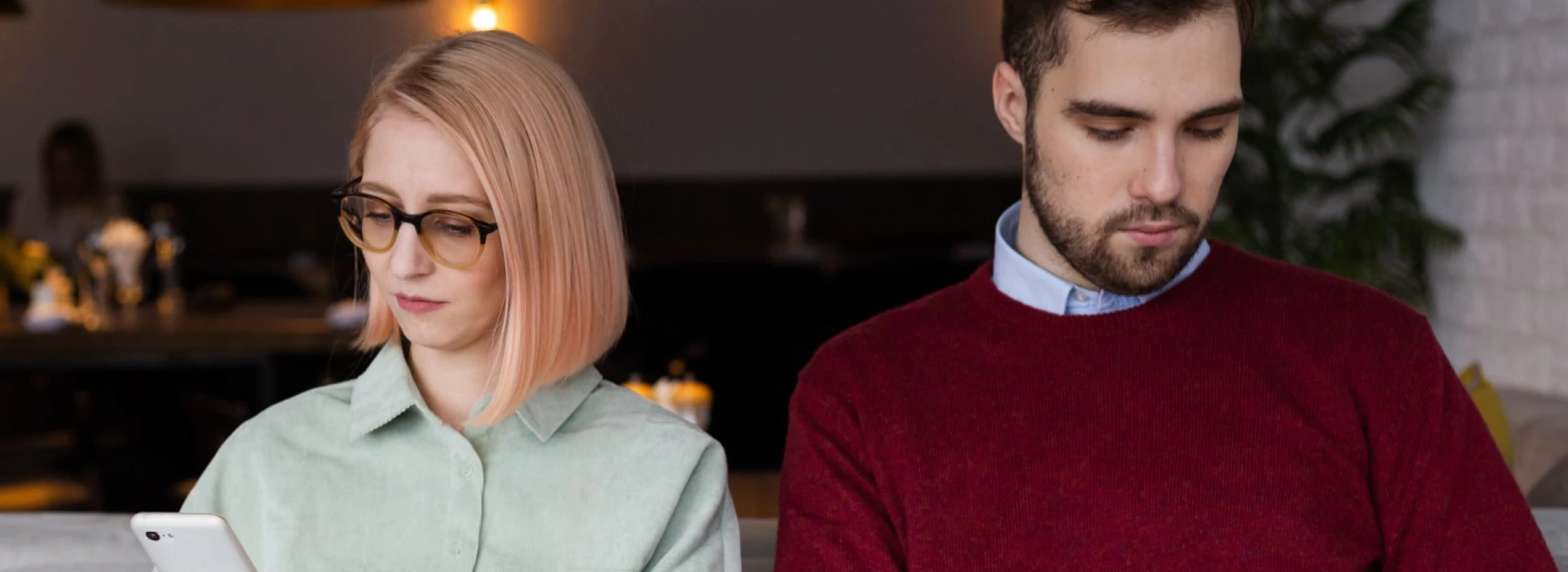 young couple on boring date stuck in gadgets