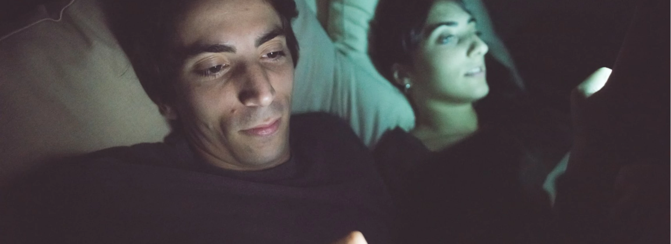 young couple in bed using computer