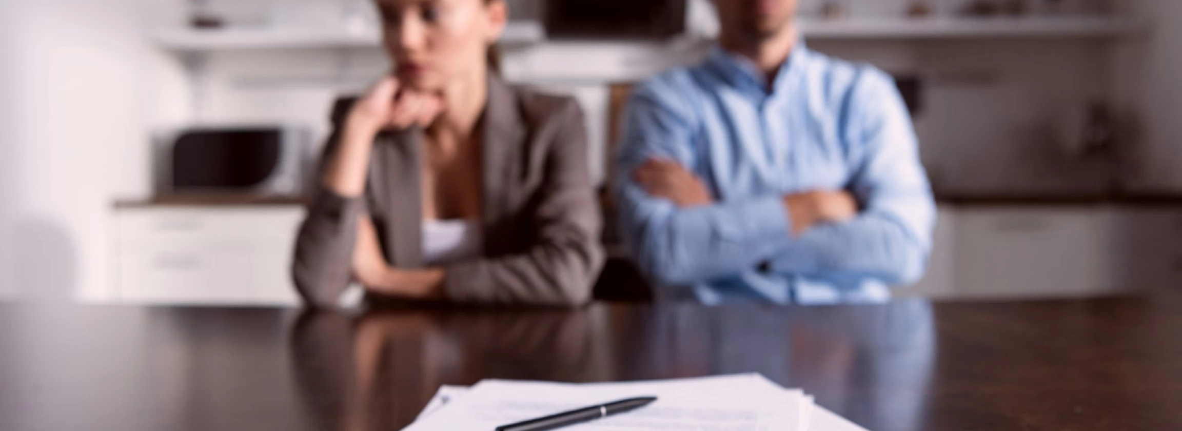 a selective focus on a couple seated at a table holding divorce papers