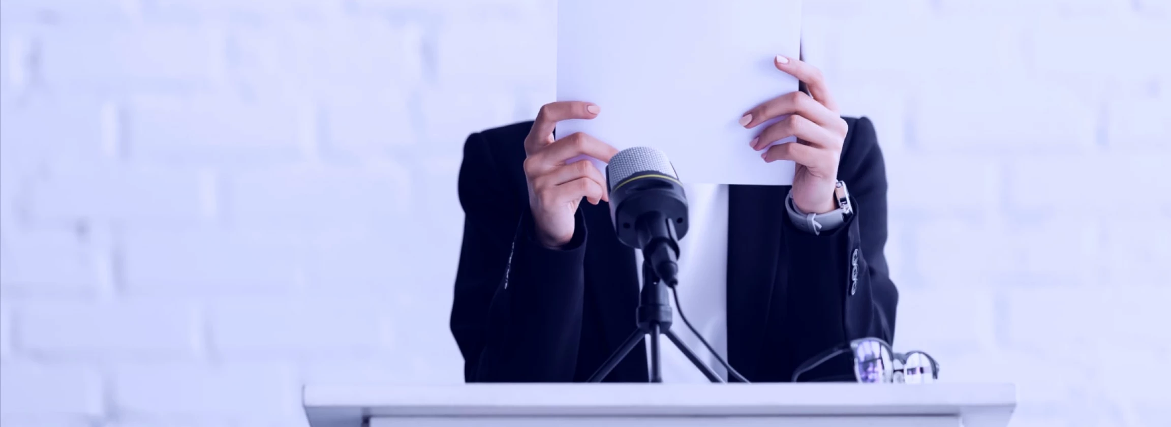 fearful of public speaking a young speaker stands on the podium tribune covering his face