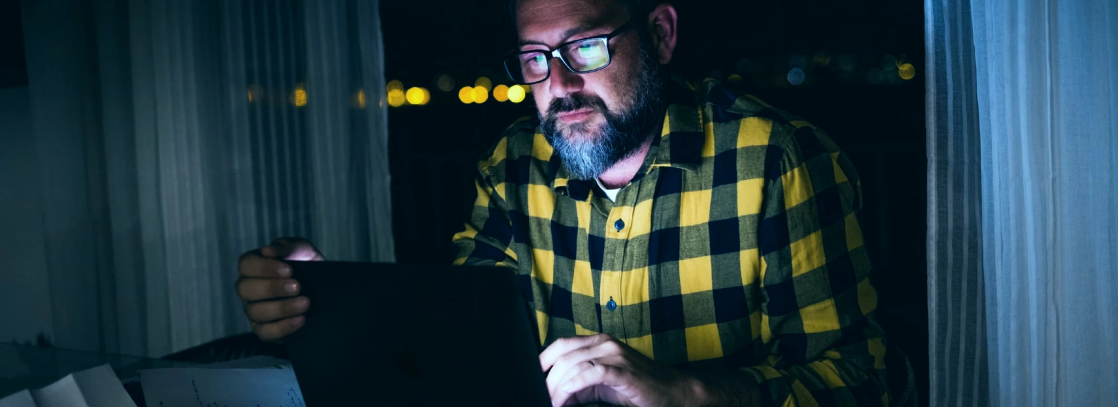 at home at night a man is using a laptop and watching videos on a computer