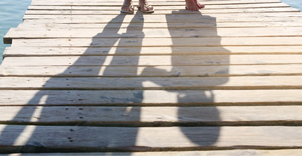 shadows of child and adult on jetty