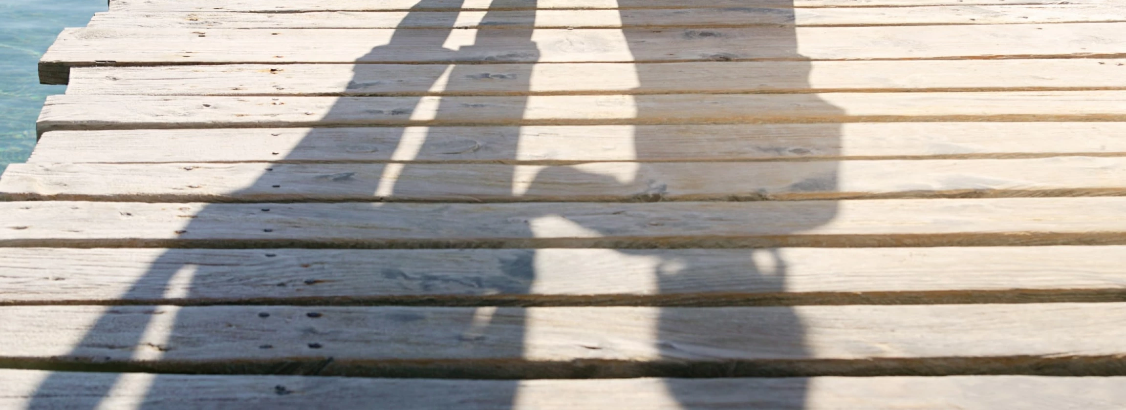 shadows of child and adult on jetty