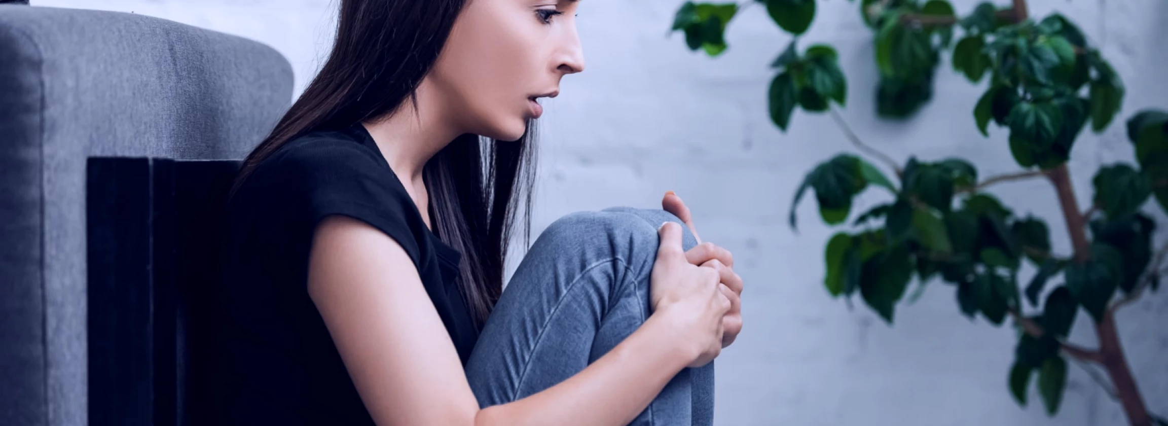 young woman is sitting on the floor at home having a panic attack