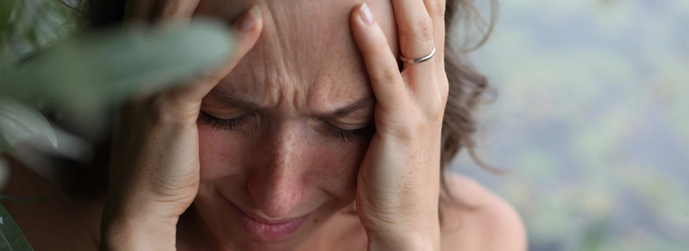 a young woman holds her head and cries with strong emotions on her face