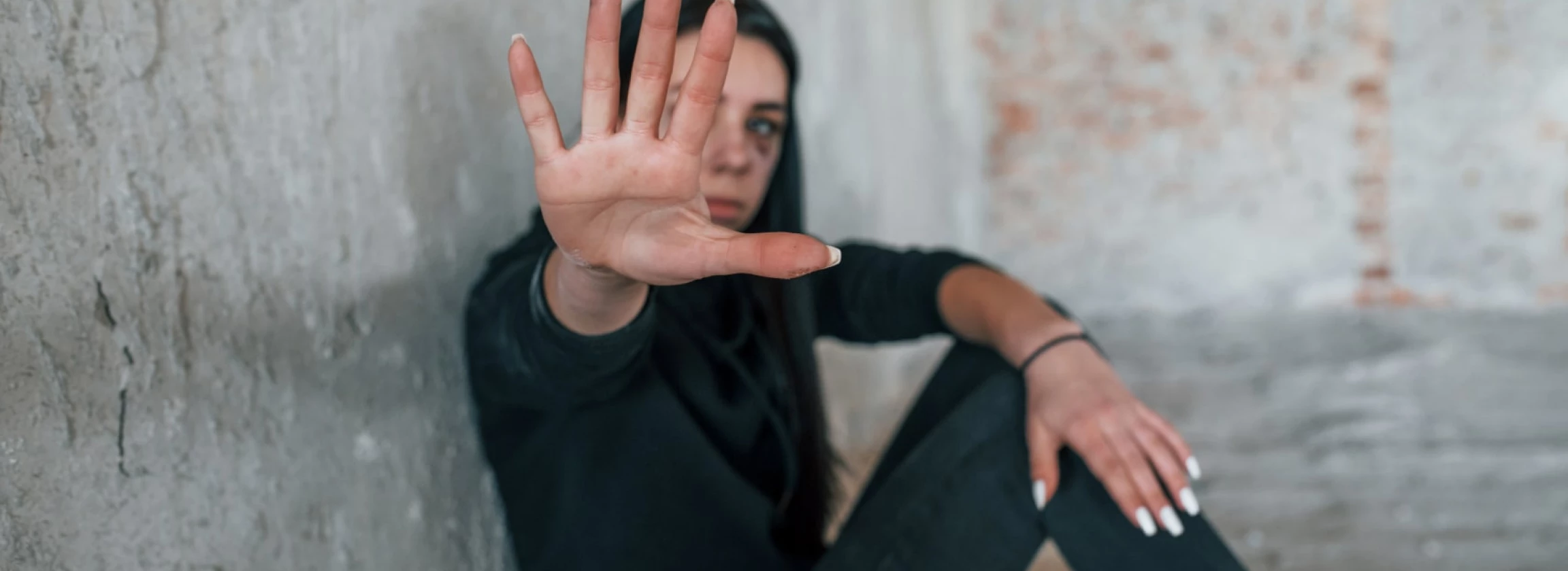young hurt woman in black clothes sitting on the floor of abandoned building