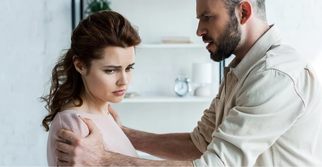 Young man looking angry but not screaming next to a woman who’s also upset