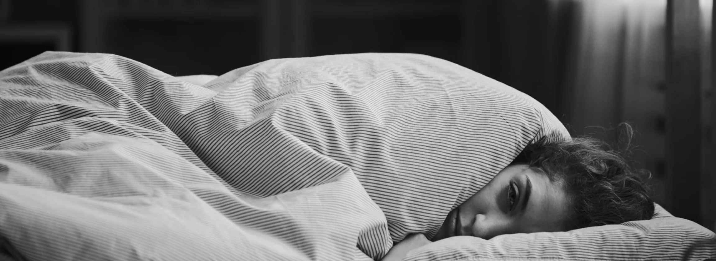 woman curled up in bed in the fetus position