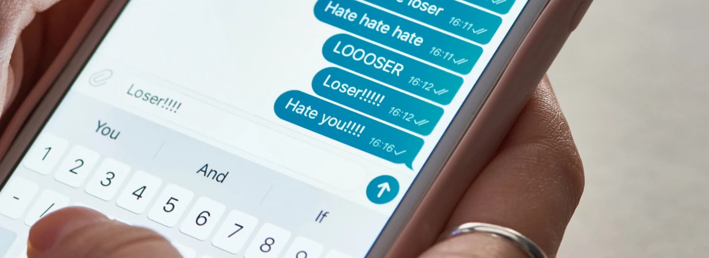 panoramic shot of abuser sending offensive messages while using smartphone