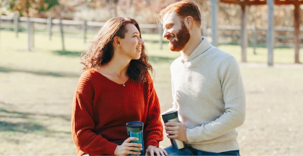 a young couple sits on a fence and enjoys each other's company