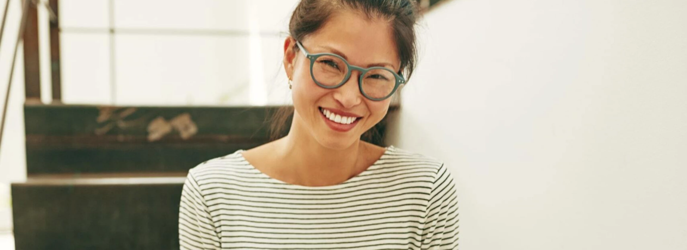smiling asian businesswoman sitting on stairs reading a text message