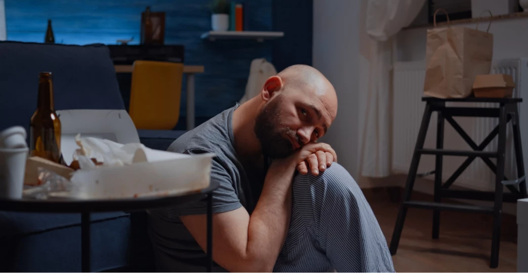 depressed man sitting on floor looking at camera with disappointed expression