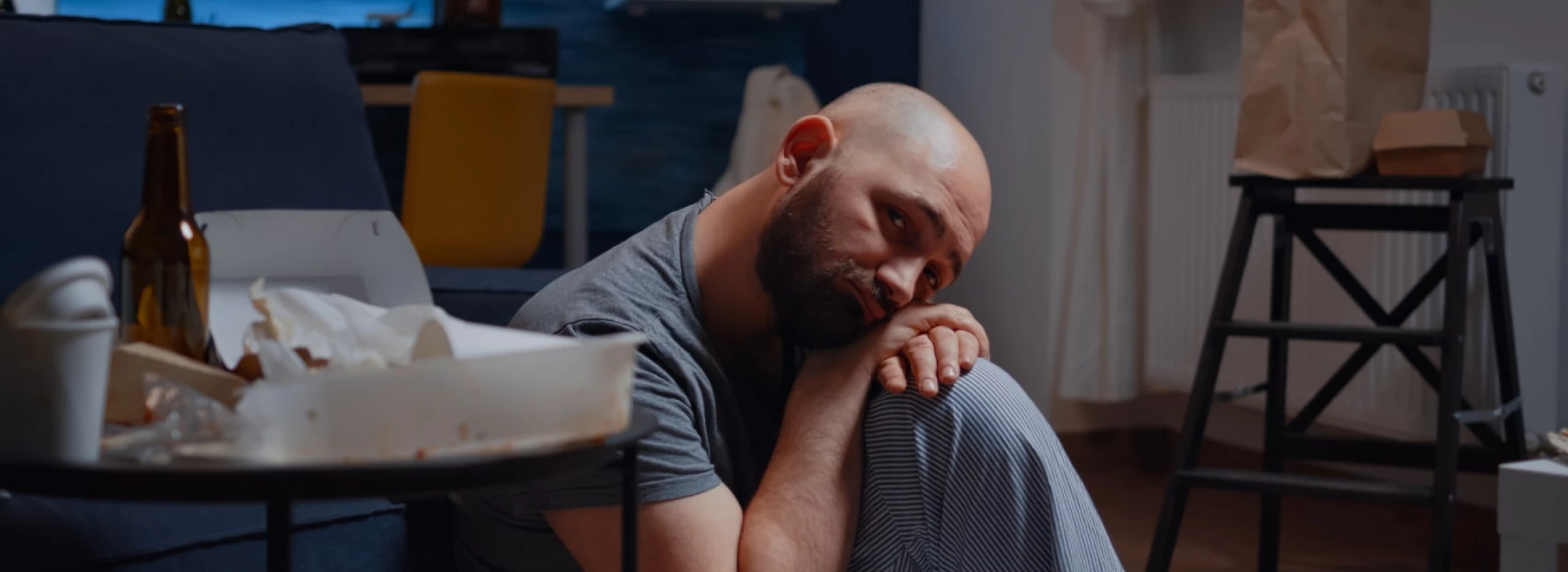 depressed man sitting on floor looking at camera with disappointed expression