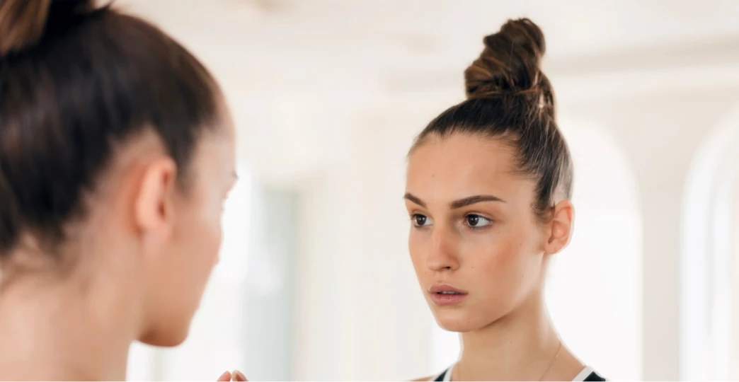 woman looking at her reflection in the mirror