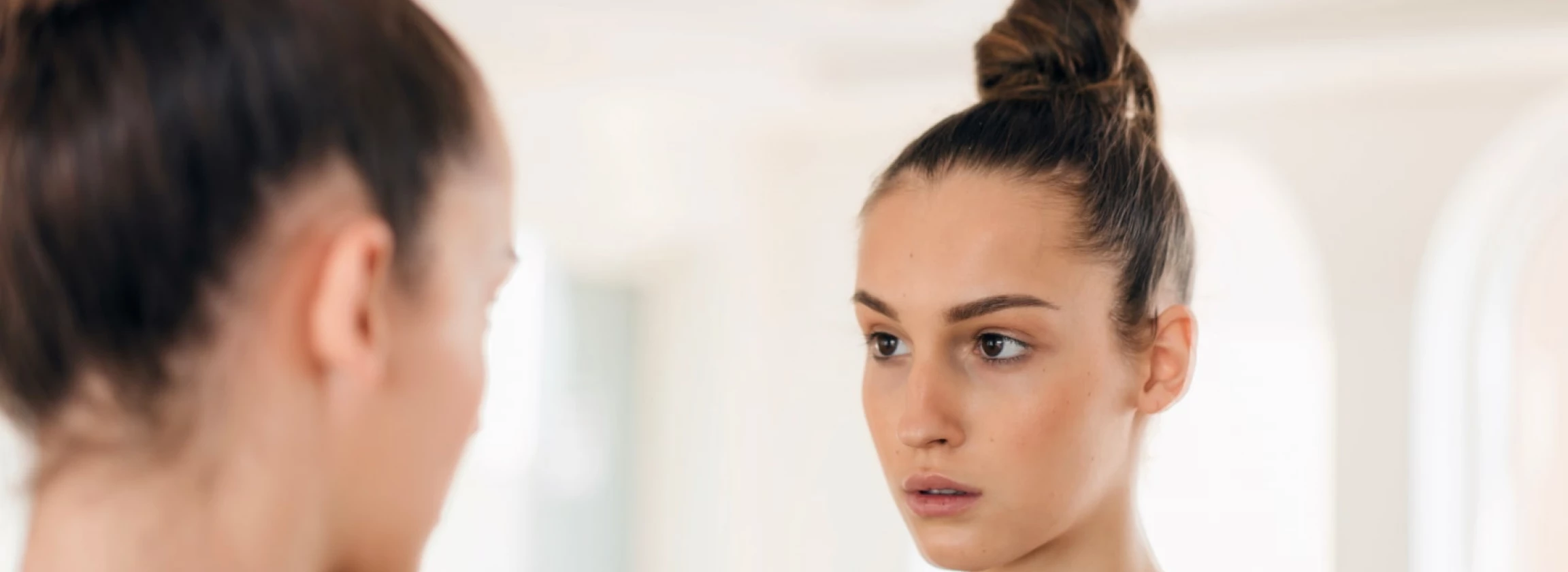 woman looking at her reflection in the mirror